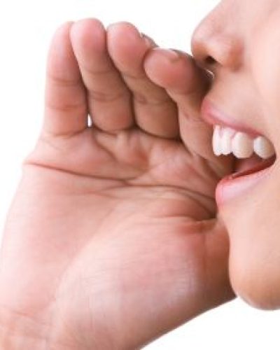 Woman saying something while holding her hand to her mouth as if wanting to make sure she is heard