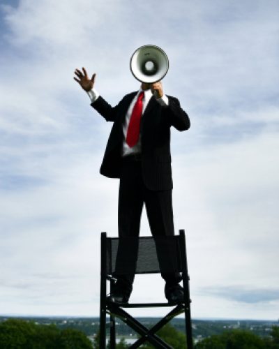 Man standing on chair using megaphone